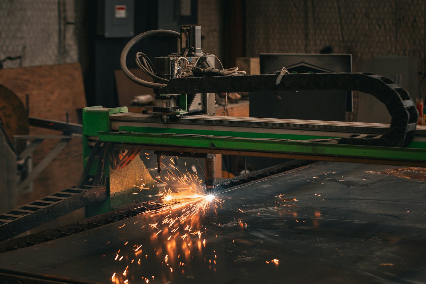 Taglio al plasma CNC che crea scintille su lamiera.