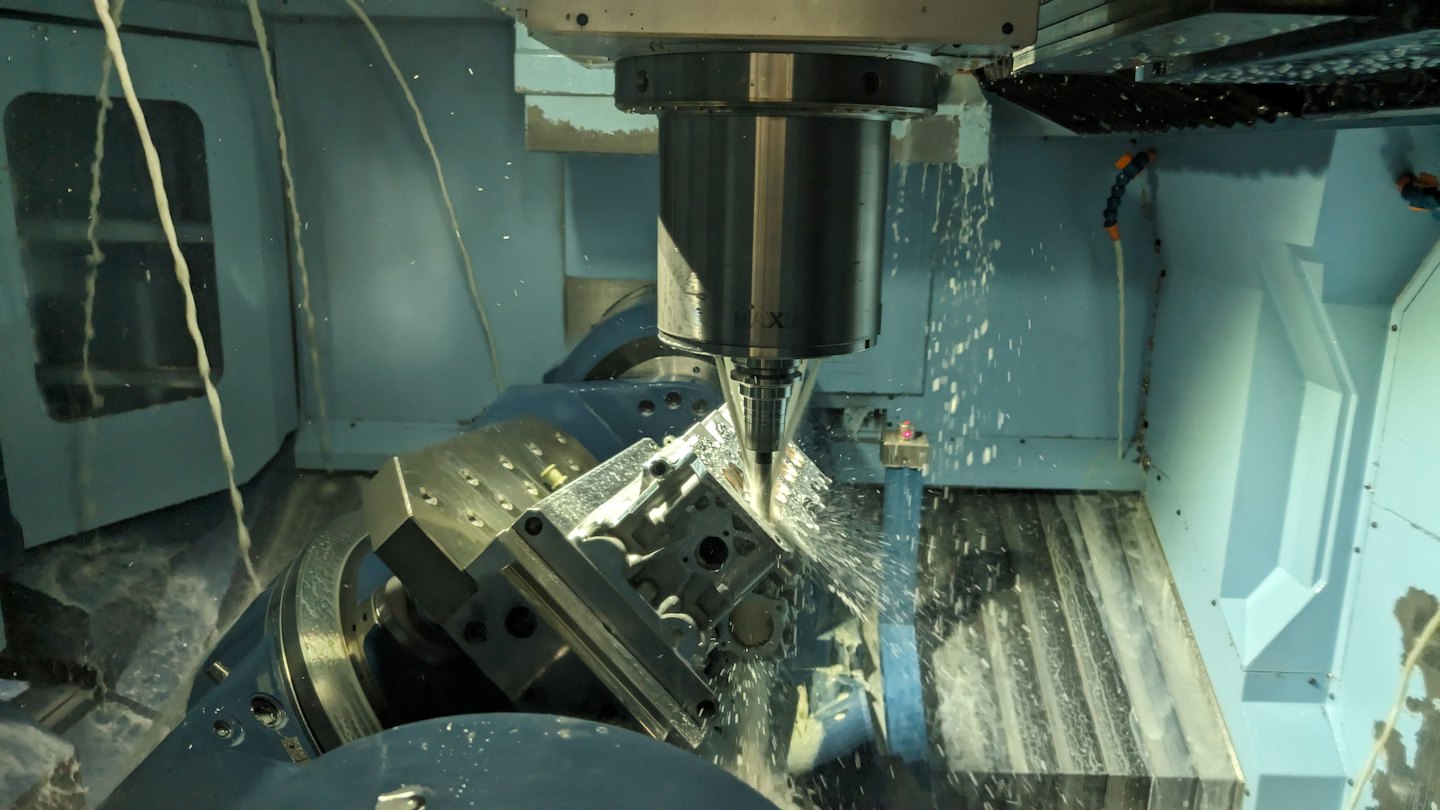 Fresatrice CNC spruzza liquido refrigerante su un pezzo di metallo.